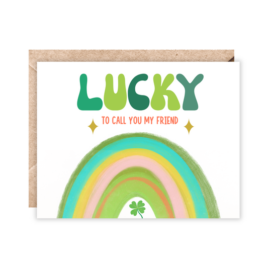 Greeting card with cream background and a rainbow on the bottom in shades of green, yellow, orange and teal. Text reads Lucky in big bubble letters in shades of green. Under Lucky reads to call you my friend.