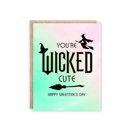 Pink and green ombre colored background with the text You're wicked cute happy valentine's day. Has a witch hat, broomstick and flying witch on the card